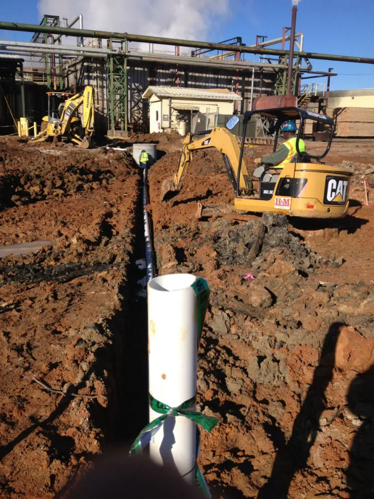 A pipe laying in the ground next to a construction site.