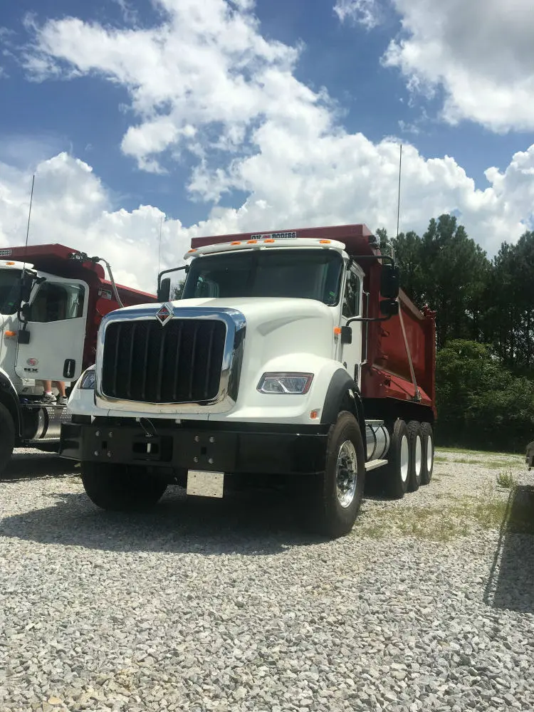 Two dump trucks parked in a gravel lot.